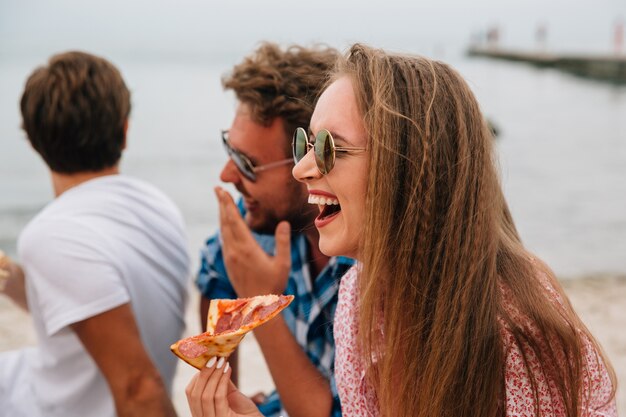 Divertidos amigos atractivos pasar tiempo con placer en la playa, sonriendo alegremente