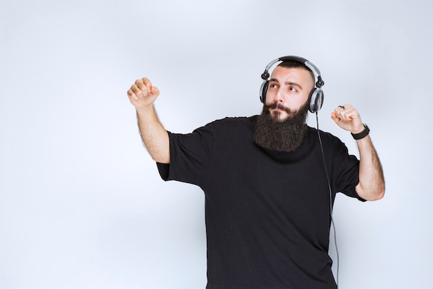 Dj con barba con auriculares bailando y sintiéndose activo.