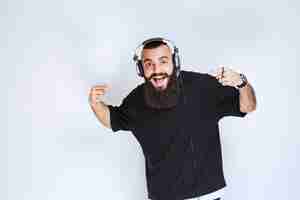 Foto gratuita dj con barba con auriculares bailando y sintiéndose activo.