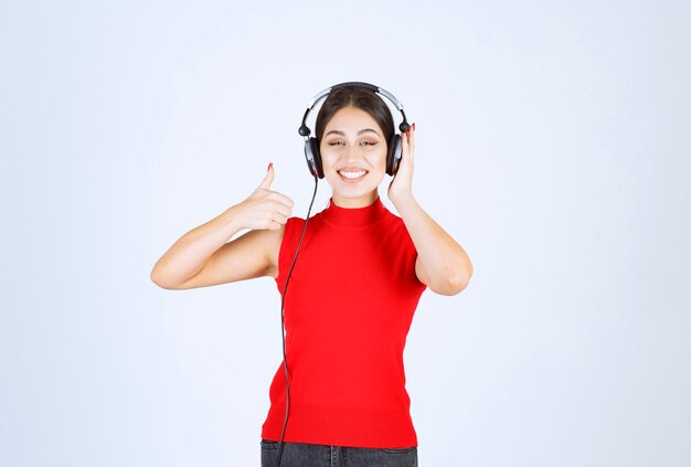 Dj en camisa roja usando audífonos y disfrutando de la música.