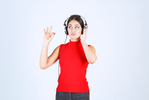 Dj en camisa roja usando audífonos y disfrutando de la música.