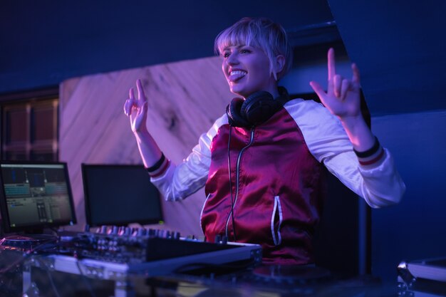 Dj femenina divirtiéndose mientras toca música en el bar