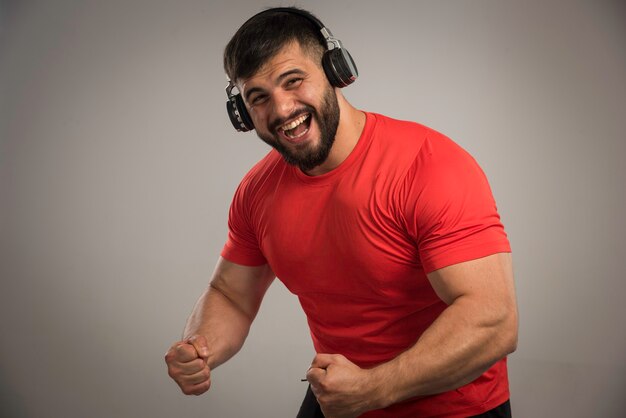 Foto gratuita dj masculino en camisa roja con auriculares y bailando.