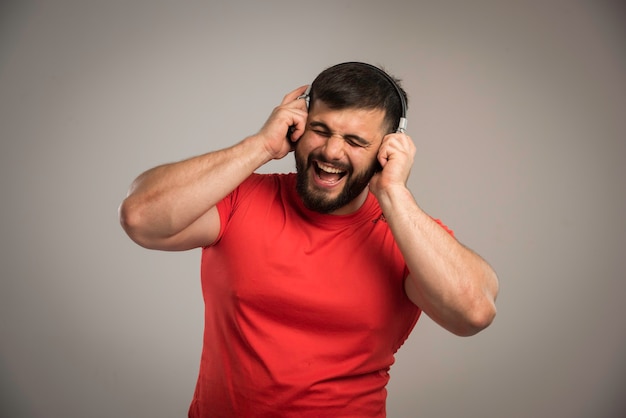 Dj masculino en camisa roja usando audífonos y cantando