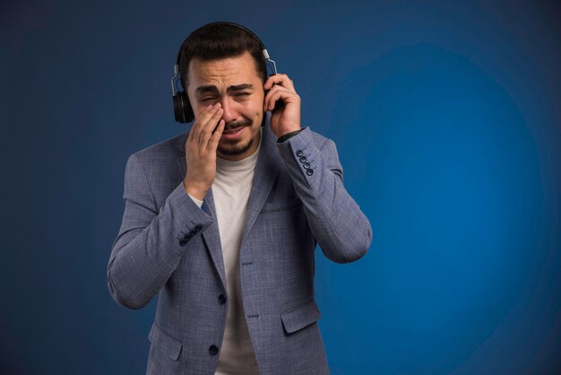 Dj masculino en traje gris escuchando auriculares y se toca.