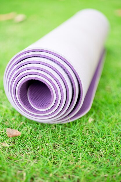 Doblado ejercicio, fitness o yoga mat en el césped