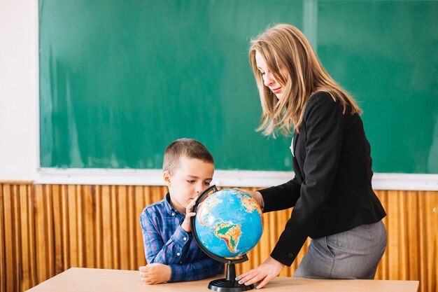 Docente y estudiante chico trabajando con globo