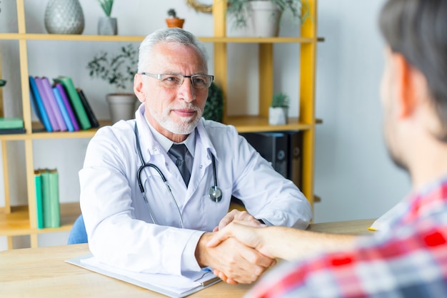 Foto gratuita doctor amistoso agitando la mano del paciente