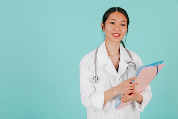 Doctor asiático sonriente con estetoscopio y carpeta