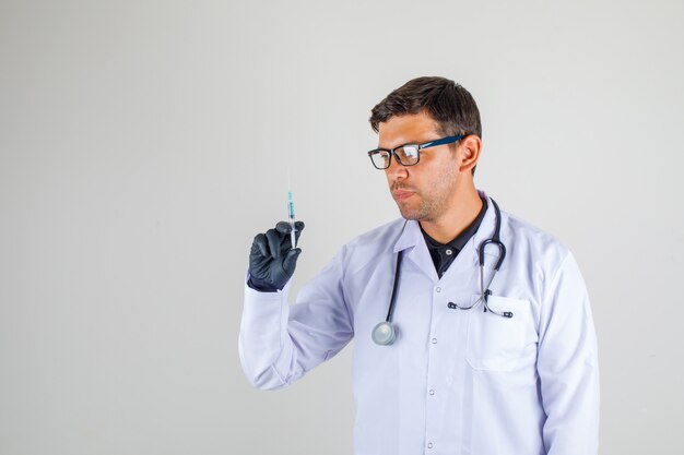 Doctor en bata blanca con estetoscopio sosteniendo la jeringa