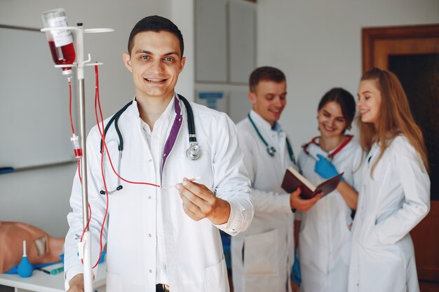 Doctor en bata tiene un gotero con medicamentos