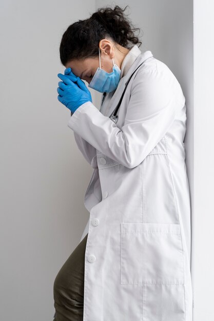 Doctor cansado de tiro medio con máscara en el trabajo