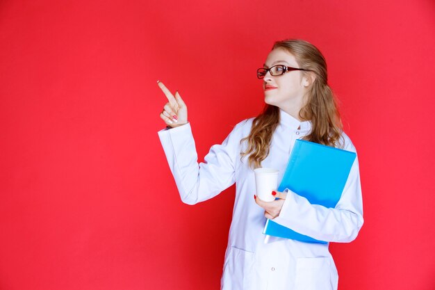 Doctor con una carpeta azul que muestra la izquierda.