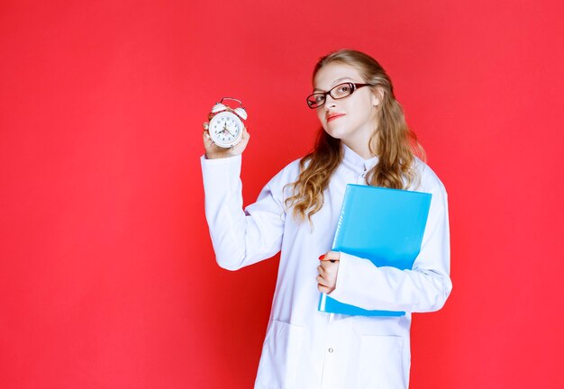 Doctor con una carpeta azul sosteniendo un reloj.