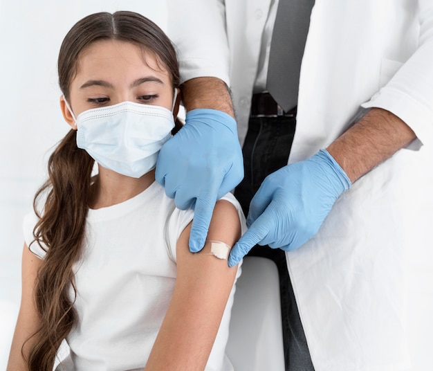 Doctor colocando un vendaje en el brazo de una niña