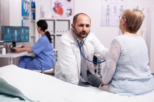 Doctor comprobando el problema respiratorio de la mujer mayor enferma en el hospital