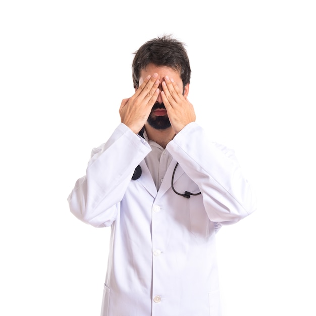 Doctor cubriendo sus ojos sobre fondo blanco aislado