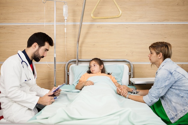 Doctor dando la noticia a la niña paciente y a la madre en el hospital