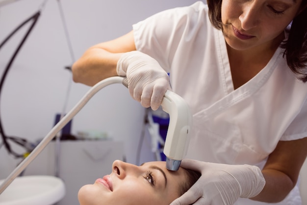 Doctor dando tratamiento cosmético a paciente femenino