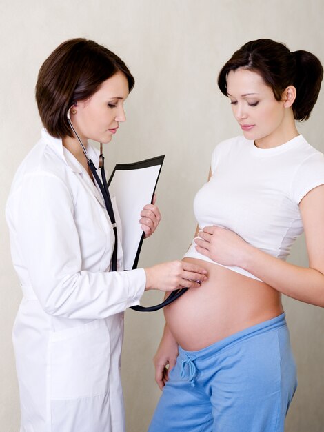 Doctor escucha el vientre de una mujer embarazada