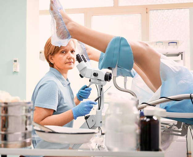 Doctor examinando a mujer con colposcopio en clínica moderna