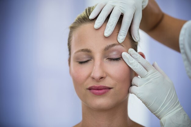 Doctor examinando pacientes femeninos cara de tratamiento cosmético