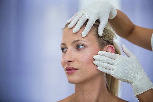 Doctor examinando pacientes femeninos cara de tratamiento cosmético