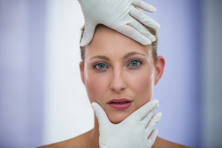 Foto gratuito doctor examinando pacientes femeninos cara de tratamiento cosmético