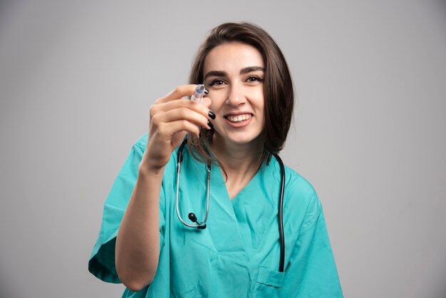 Doctor feliz en uniforme posando con jeringa. Foto de alta calidad