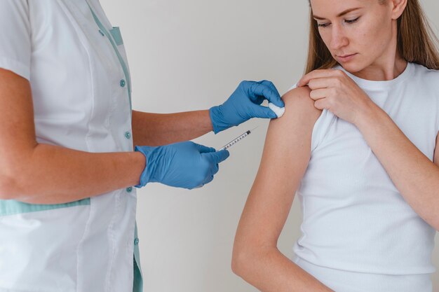 Doctor con guantes administrando la vacuna a la mujer