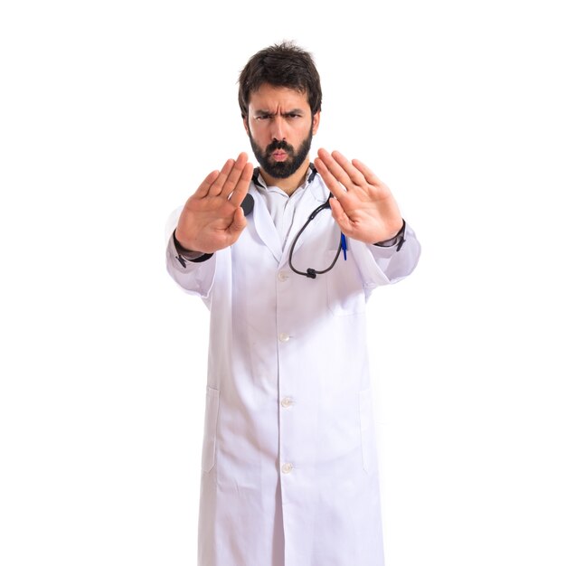 Doctor haciendo señal de stop sobre fondo blanco