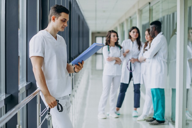 Doctor hombre con documentos de diagnóstico en el pasillo del hospital.