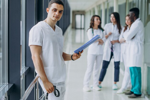 Doctor hombre con documentos de diagnóstico en el pasillo del hospital.