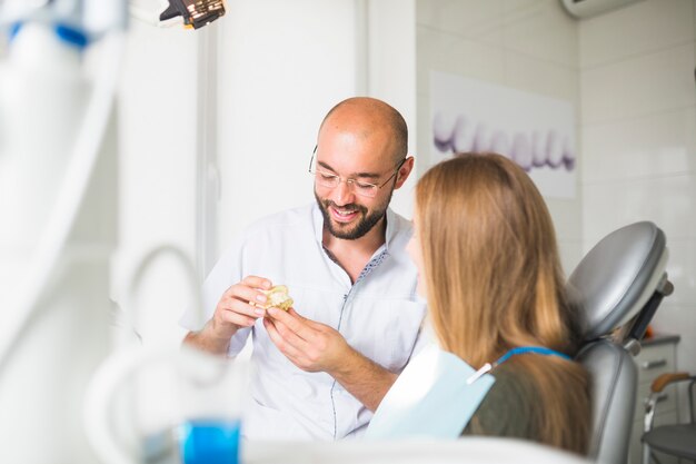 Doctor hombre hablando con paciente mostrando mandíbula dental