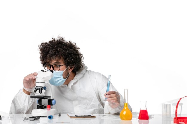 Doctor hombre en traje de protección y máscara con microscopio en blanco