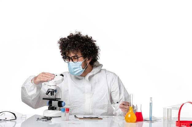 Doctor hombre en traje de protección y máscara con microscopio en blanco