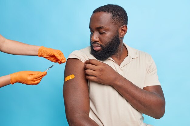 El doctor inyecta la vacuna contra el coronavirus en el brazo del hombre. Inoculación del paciente en hombro.