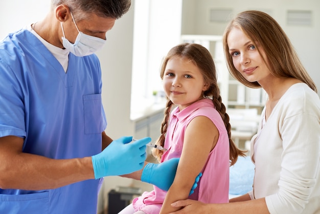 Doctor inyectando vacuna a la niña