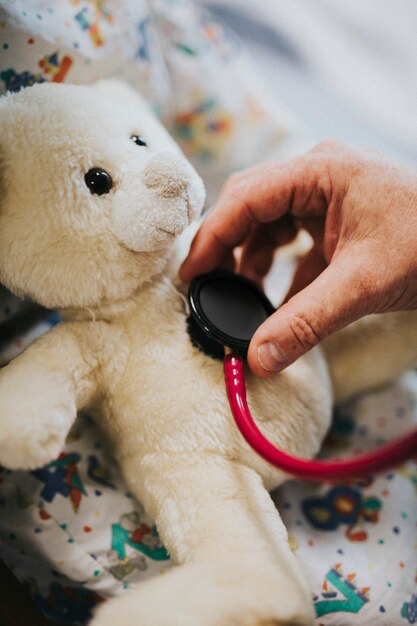 Doctor juguetonamente comprobando el latido del corazón de un oso de peluche