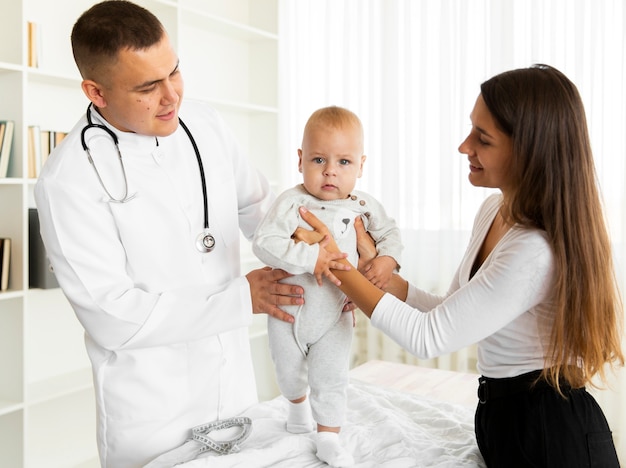 Doctor y madre ayudando al bebé a caminar