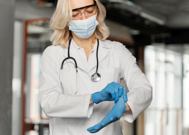 Doctor con máscara médica poniéndose guantes médicos