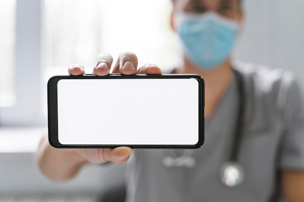 Doctor con máscara médica con smartphone