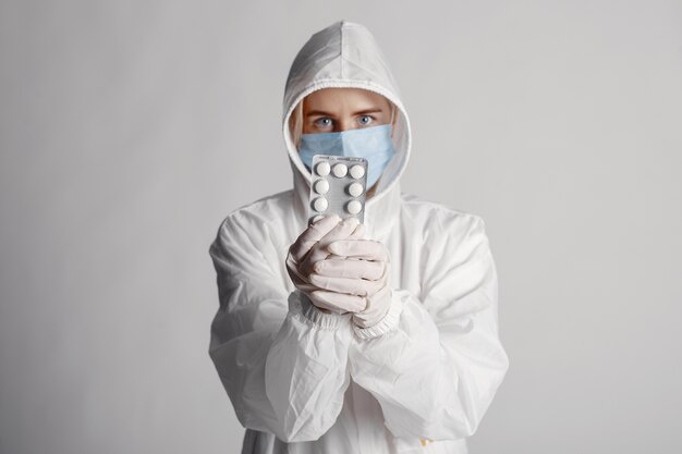 Doctor en una máscara médica. Tema de coronavirus. Aislado sobre fondo blanco. Mujer con pastillas.