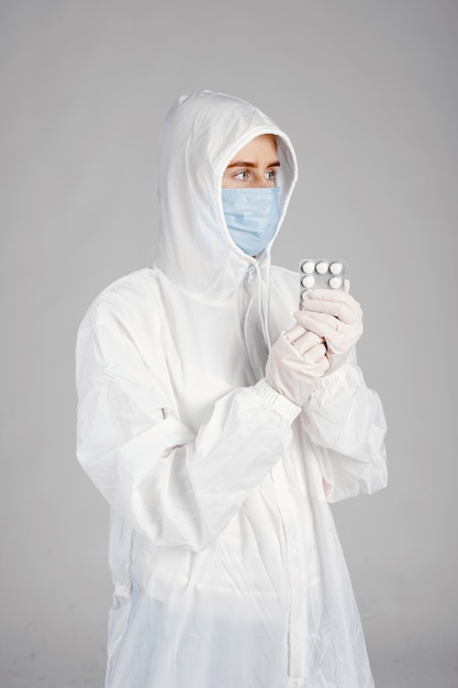 Doctor en una máscara médica. Tema de coronavirus. Aislado sobre pared blanca. Mujer con pastillas.