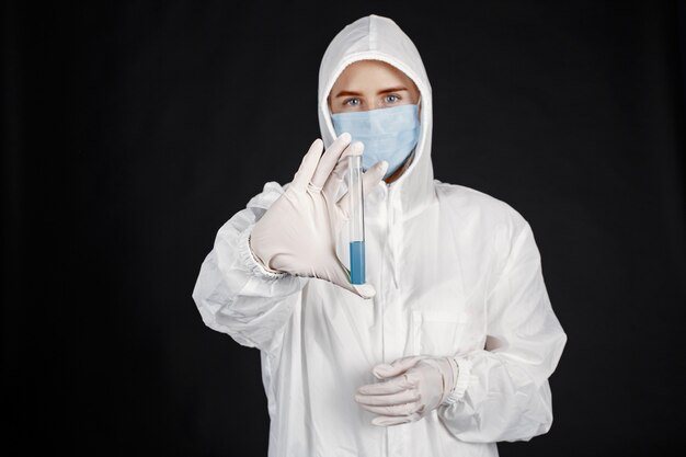 Doctor en una máscara médica. Tema de coronavirus. Aislado sobre pared negra. Mujer en traje de protección.