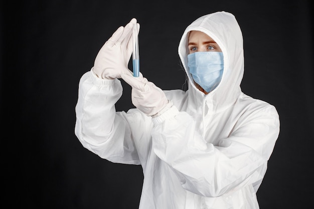 Doctor en una máscara médica. Tema de coronavirus. Aislado sobre pared negra. Mujer en traje de protección.