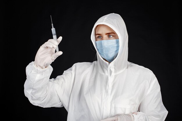 Doctor en una máscara médica. Tema de coronavirus. Aislado sobre pared negra. Mujer en traje de protección.