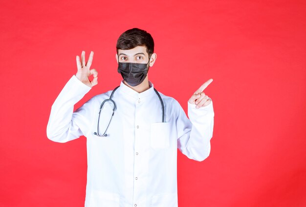 Doctor en máscara negra con estetoscopio en el cuello.