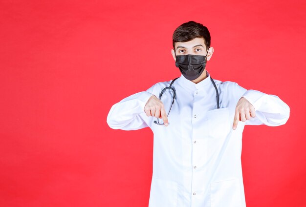 Doctor en máscara negra con estetoscopio en el cuello.