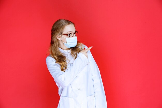 Doctor en mascarilla apuntando hacia la derecha.